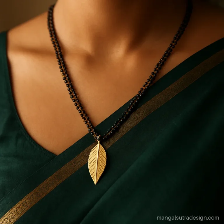 Long gold mangalsutra with a leaf motif pendant worn with a silk saree