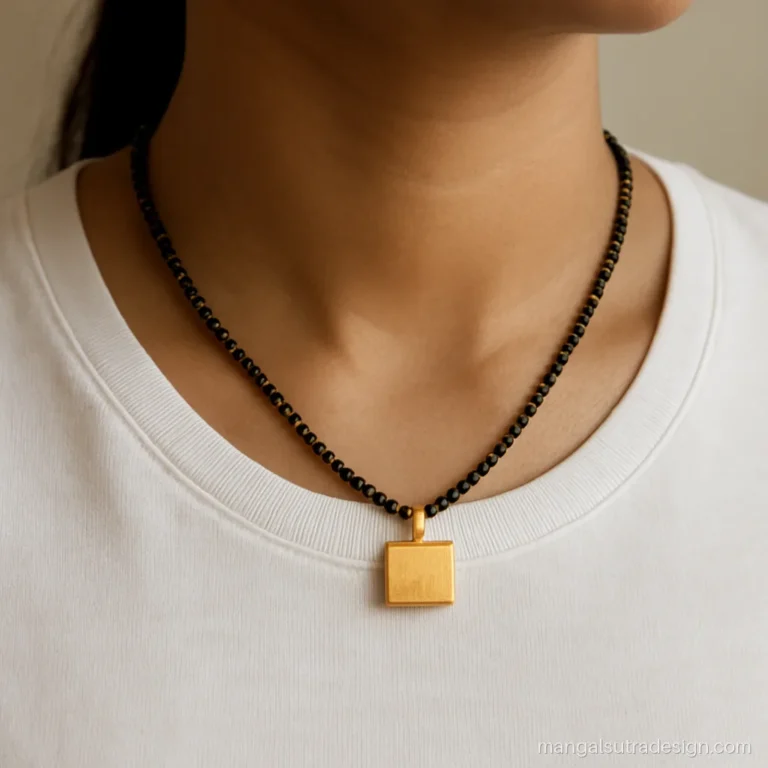 Woman wearing a short mangalsutra with a small brushed gold square pendant over a plain t-shirt